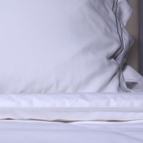 Sand colored lumbar pillow on top of a white sheet